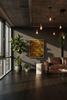 Modern living room with a brown leather sofa, potted plants, and abstract art on the wall.