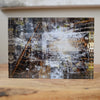 A free-standing art tile featuring a black, white, and gray industrial-themed design with hints of copper.