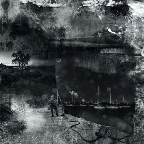 A black and white image featuring a dramatic coastal scene with a lone figure on the beach at night, boats in the background, and a sky filled with clouds.