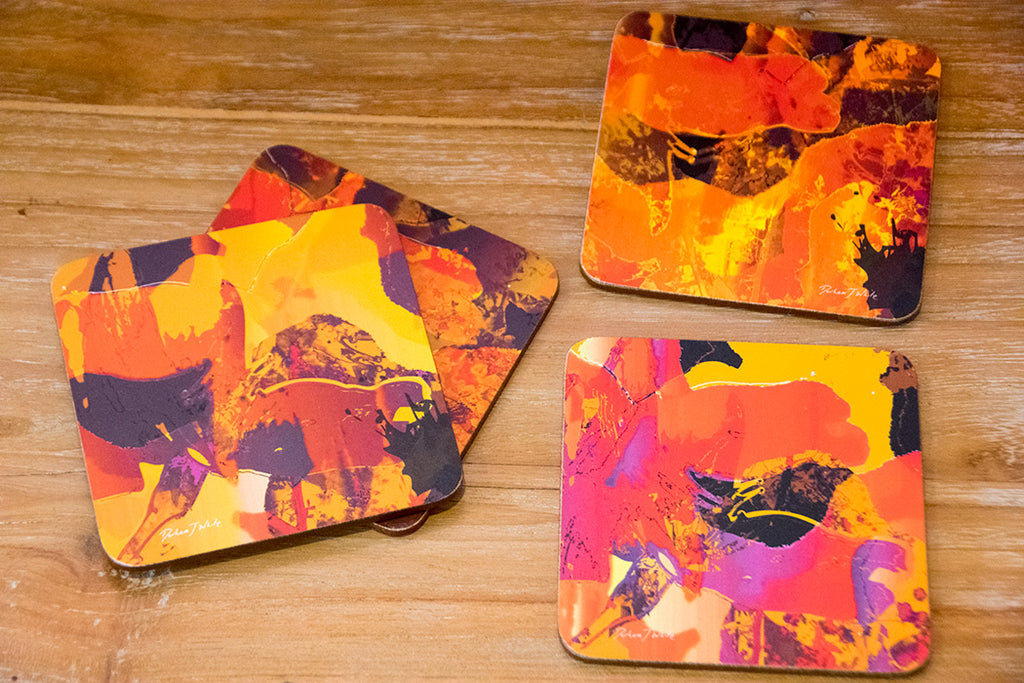 Four colourful coasters with abstract Japanese blossom in orange designs on a wooden surface