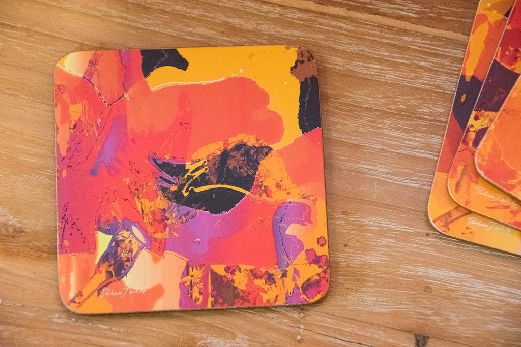 Four colourful coasters with abstract Japanese blossom in orange designs on a wooden surface