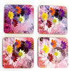 A set of four pink coasters with a sunflower design, featuring vibrant yellow, orange, and purple accents.