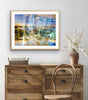“Keeping Up a Pier Glance 2” glass-framed fine art print by Durham J White, featuring a layered photographic artwork of the Mornington waterfront in luminous pastel blues, subtle lemon highlights, and warm orange accents in a neutral interior space.
