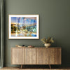“Keeping Up a Pier Glance 2” glass-framed fine art print by Durham J White, featuring a layered photographic artwork of the Mornington waterfront in luminous pastel blues, subtle lemon highlights, and warm orange accents. Featured in a glass frame in a sage toned living or bedroom space.