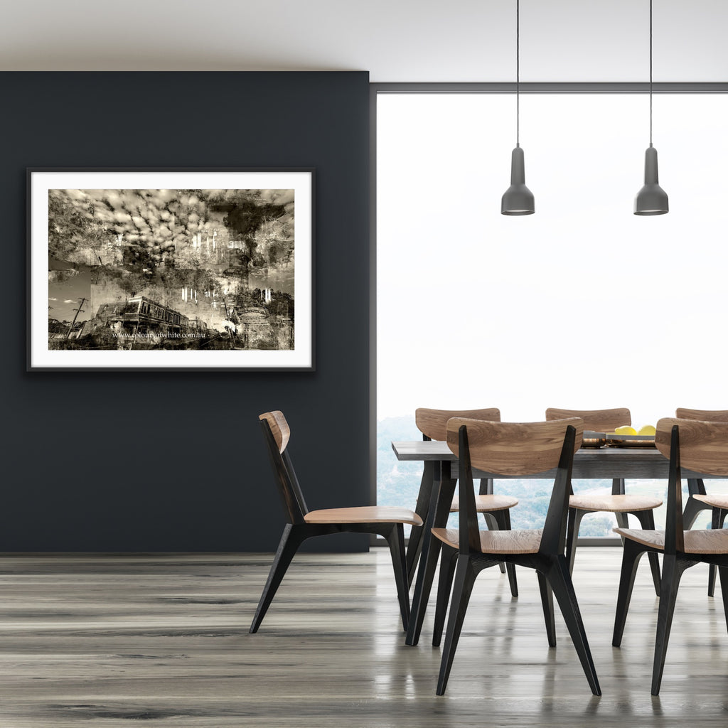“Shades of the Historical Present Past” glass framed fine art print by Durham J White, featuring a monochromatic layered photographic artwork of Piper Street in Kyneton in rich greys, crisp whites, and ink blacks. Styled on a dark grey wall in a neutral toned interior.
