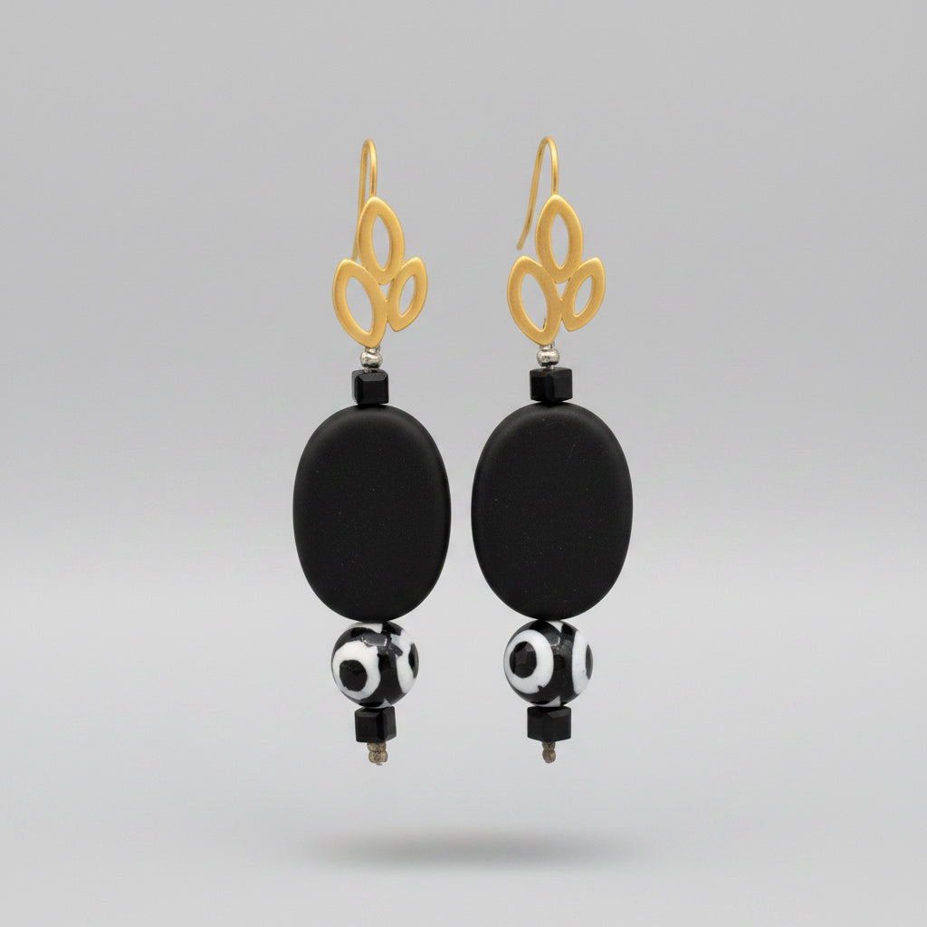 A pair of gold-plated triple leaf earrings with matt black stones and black and white patterned balls