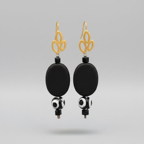 A pair of gold-plated triple leaf earrings with matt black stones and black and white patterned balls