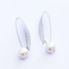 A pair of silver leaf earrings with a single freshwater pearl on each hook.