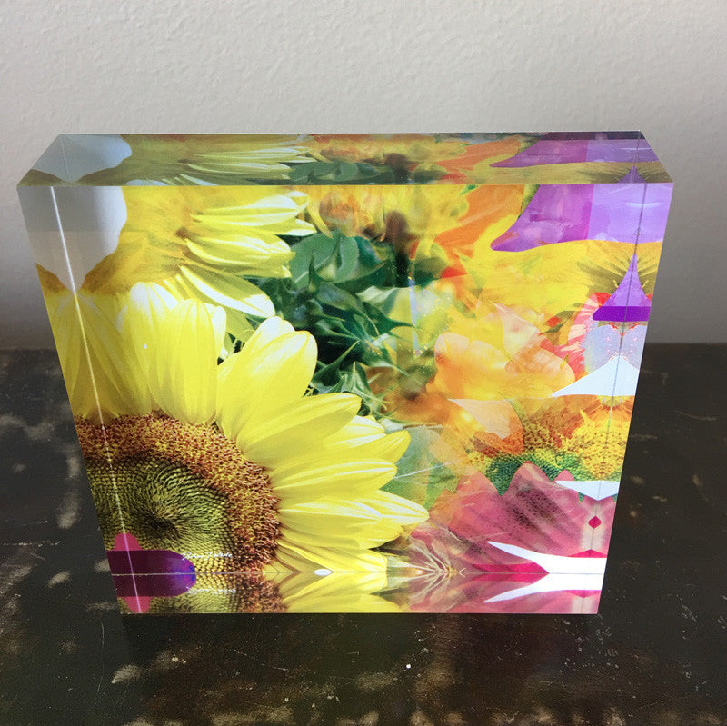 A decorative tile featuring a colourful sunflower design with a vibrant background of soft pinks and mauves.