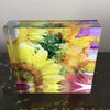 A decorative tile featuring a colourful sunflower design with a vibrant background of soft pinks and mauves.