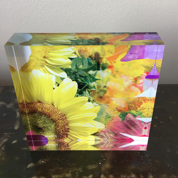 A decorative tile featuring a colourful sunflower design with a vibrant background of soft pinks and mauves.